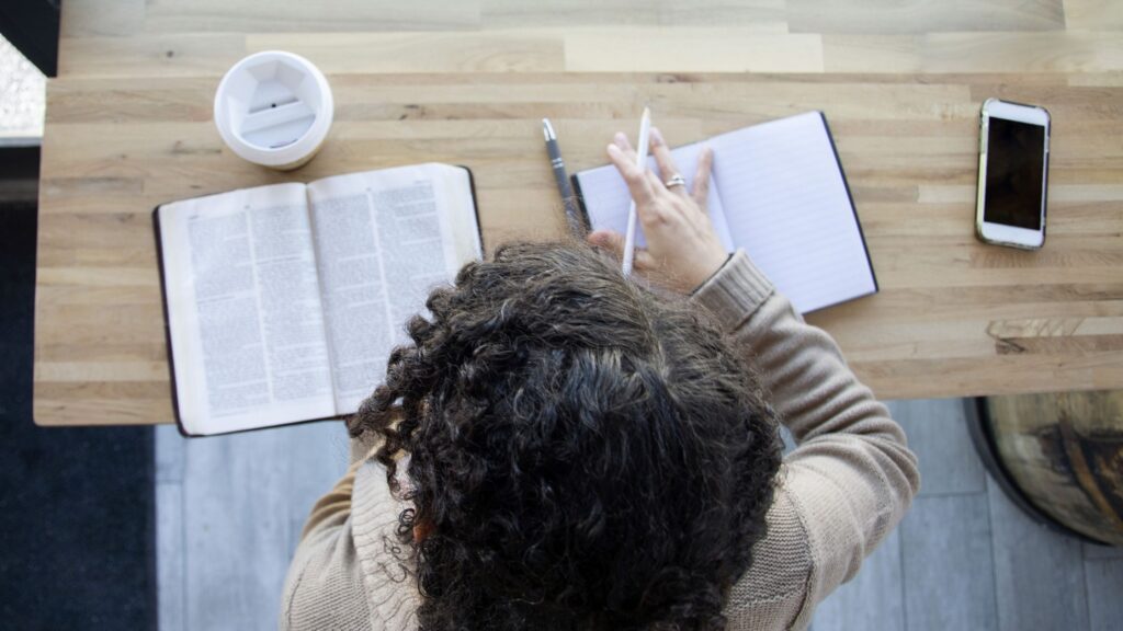 a woman studying her bible with a notebook