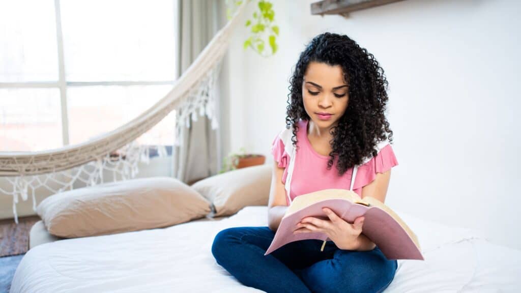 woman sitting on her bed reading the Bible
